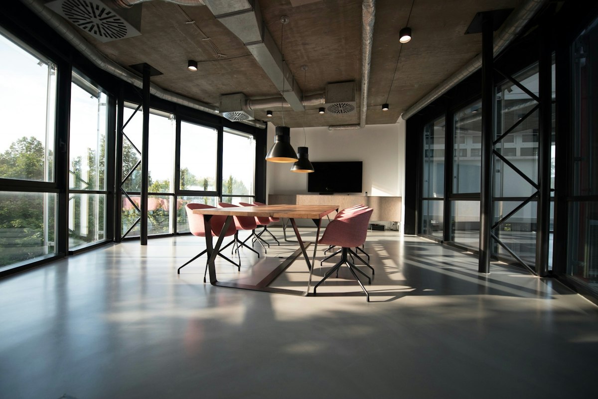Three people in a glass meeting room reviewing papers around a long table.